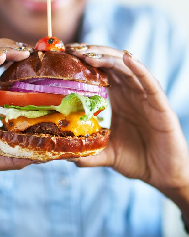 Close up view of a woman holding a delicious plant-based burger in her hands