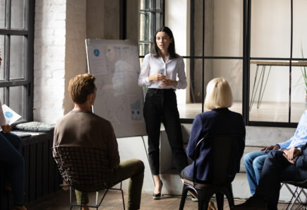 Confident woman presenting to a group of investors in an office conference room