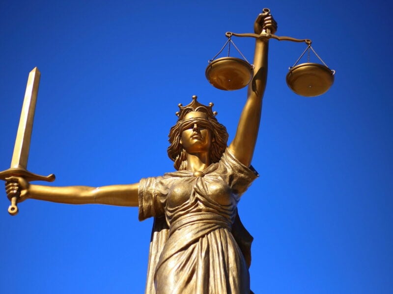 Bronze scales of justice with blue background