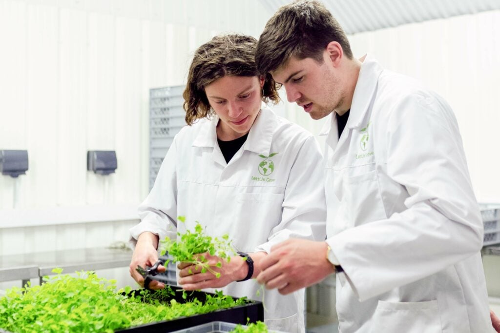 Two scientists in lab coats examining plants