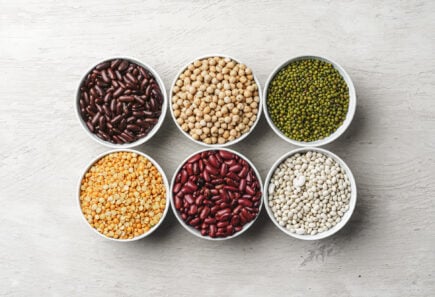 An assortment of beans in bowls on a white table, representing ingredients for plant-based meat