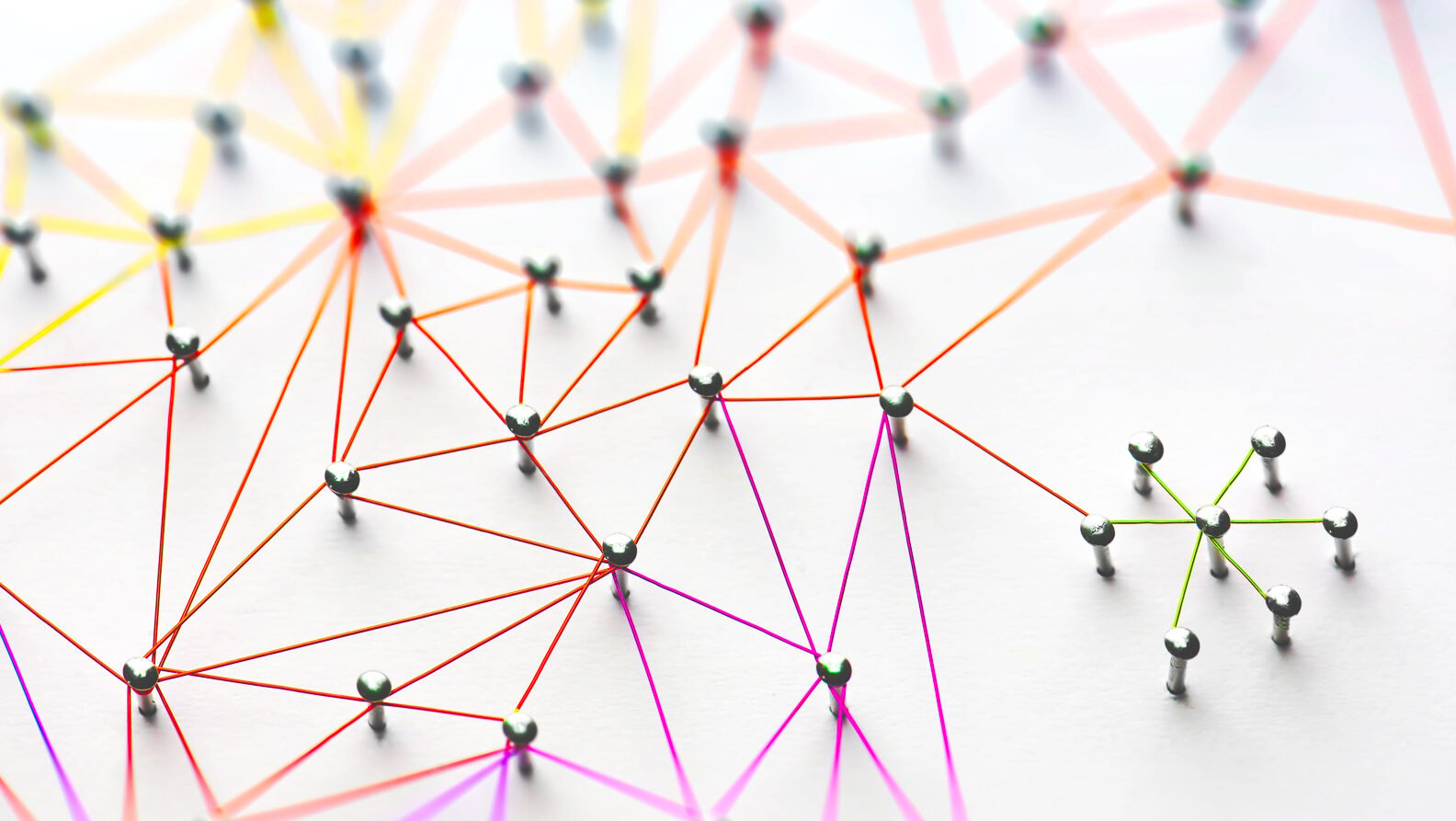 Pins connected by a web of colored string on a white background